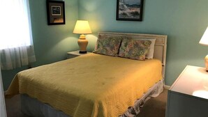 A bed with a yellow blanket, two bedside lamps, and two framed pictures on the wall. - Palmetto Walk 333 (Edisto Island)