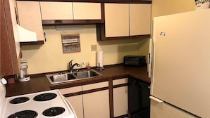 A kitchen with a stove, sink, and refrigerator. - Palmetto Walk 333 (Edisto Island)
