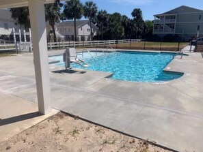 A rectangular swimming pool with a concrete deck, surrounded by a fence and palm trees. - The Retreat 5B (Edisto Island)