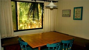 A dining area with a wooden table and two blue chairs. - Shrimpers Cove (Edisto Island)
