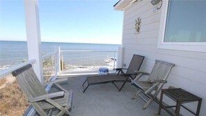 A covered outdoor area with a view of the ocean, featuring a table and four chairs. - Stormy's Newhaven (Edisto Island)