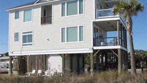 A two-story beachfront house with a balcony, a covered porch, and a palm tree. - Stormy's Newhaven (Edisto Island)