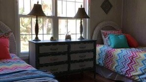 A bedroom with two beds, a dresser, and a ceiling fan. - Swamp Fox (Edisto Island)