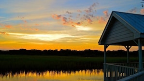 Une jetée en bois s’étendant au-dessus d’une étendue d’eau calme, avec un coucher de soleil en arrière-plan.