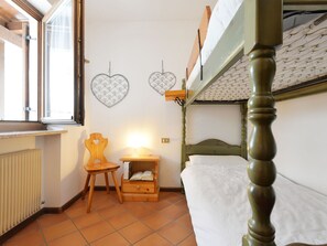 A compact room with a bunk bed, a small wooden chair, a bedside table with a lamp, and two heart-shaped wall decorations. - Casa Marmolada by Interhome (Canazei)