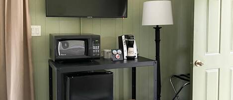Une chambre d’hôtel équipée d’un lit, d’un bureau avec une télévision, d’une machine à café et d’une lampe.