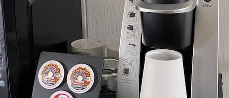 En Keurig kaffemaskine med kopholder og tre kaffekapsler mærket 'Donuts & Regular' og 'English Breakfast'.