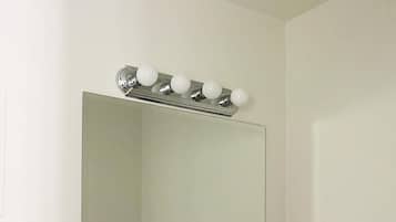 Un bagno con un ampio specchio, un lavabo e un mobile contenitore con piano in marmo.