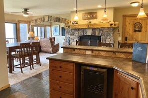 A kitchen with a stone fireplace, wooden cabinets, and a built-in dishwasher.