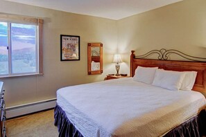 A neatly made bed with a wooden headboard, a bedside lamp, and a framed picture on the wall.