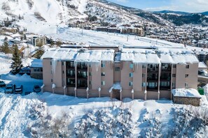 A multi-story hotel with a flat roof, surrounded by snow-covered terrain and distant mountains.