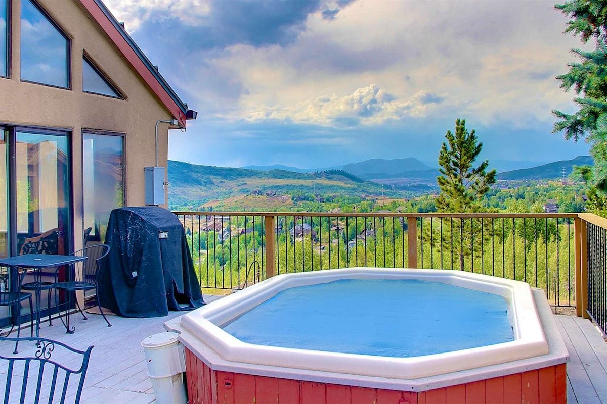 Un bain à remous sur une terrasse offrant une vue sur un paysage montagneux.
