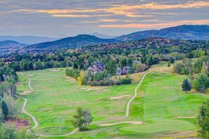 A golf course with a winding path, surrounded by trees and houses, with mountains in the background. - Amazing Views-Hot Tub-2 King Suites-Coverd Parking (Steamboat Springs)