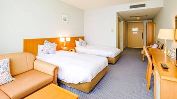 Une chambre d’hôtel avec deux lits, un canapé, un bureau et une lampe.