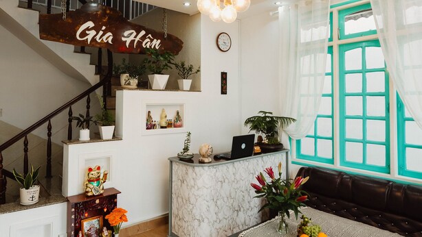 Un intérieur moderne comprenant un escalier, un comptoir d’accueil, un coin repas et un lustre.