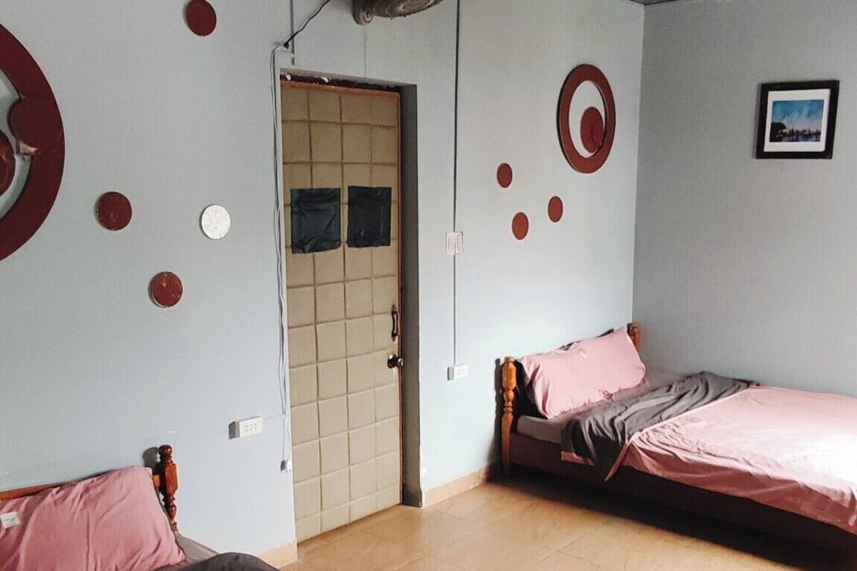 A room with two beds, a ceiling fan, and a door leading to a bathroom.