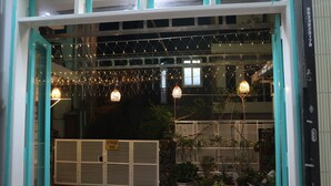 L’entrée d’un hôtel aux couleurs bleu sarcelle et blanc, dotée d’une grille et illuminée de guirlandes lumineuses.