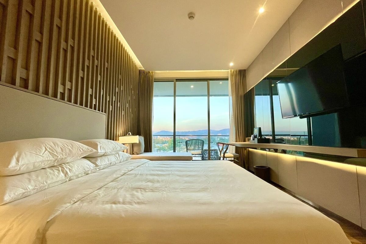 Ein modernes Hotelzimmer mit einem großen Bett, einem Schreibtisch und einem Fernseher.