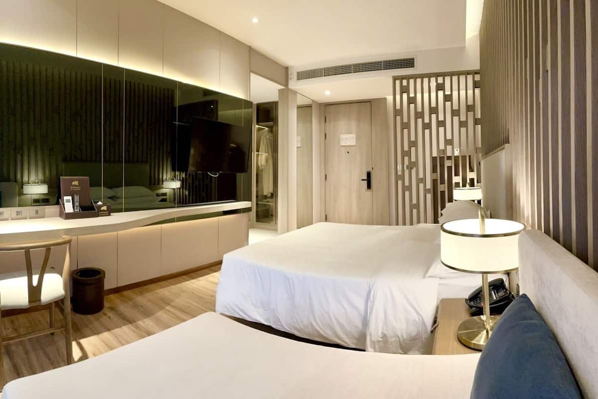 Ein modernes Hotelzimmer mit einem großen Bett, einem Schreibtisch, einem Sessel, einem Fernseher und einem Badezimmer mit Spiegel.