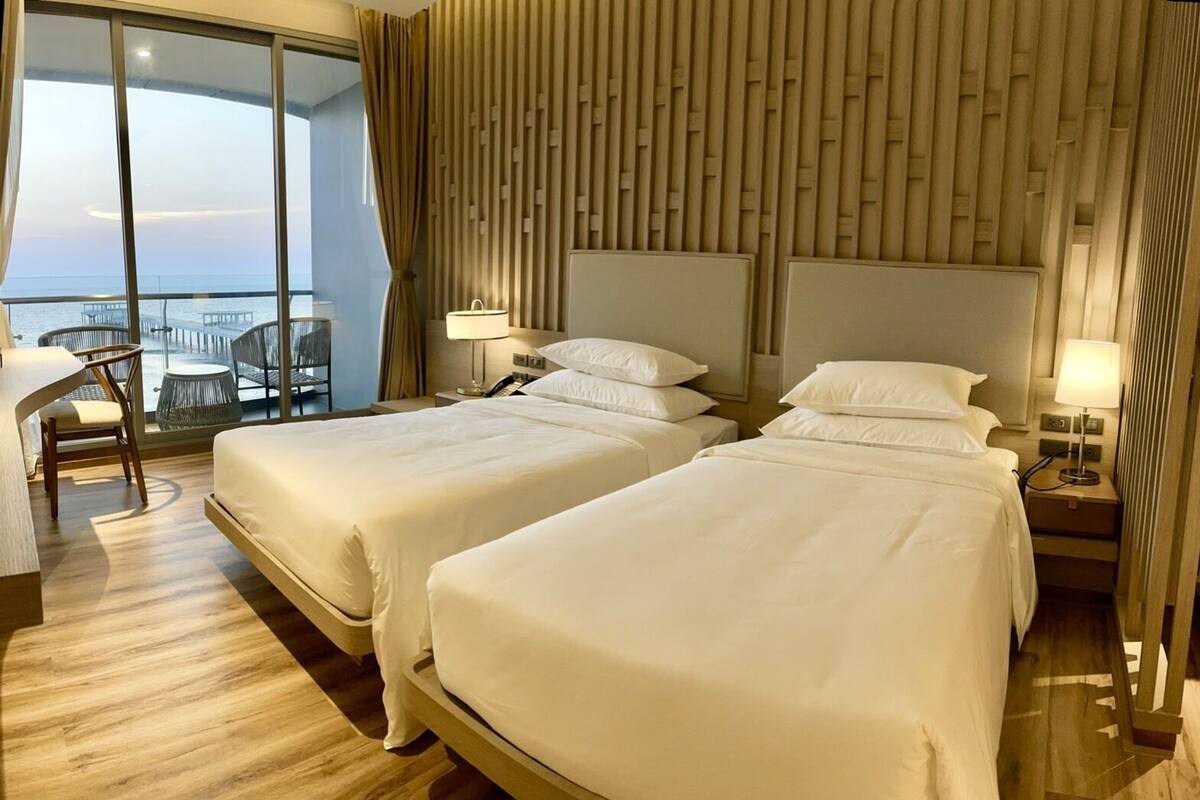 Ein Hotelzimmer mit zwei Betten, einem Schreibtisch und Meerblick.