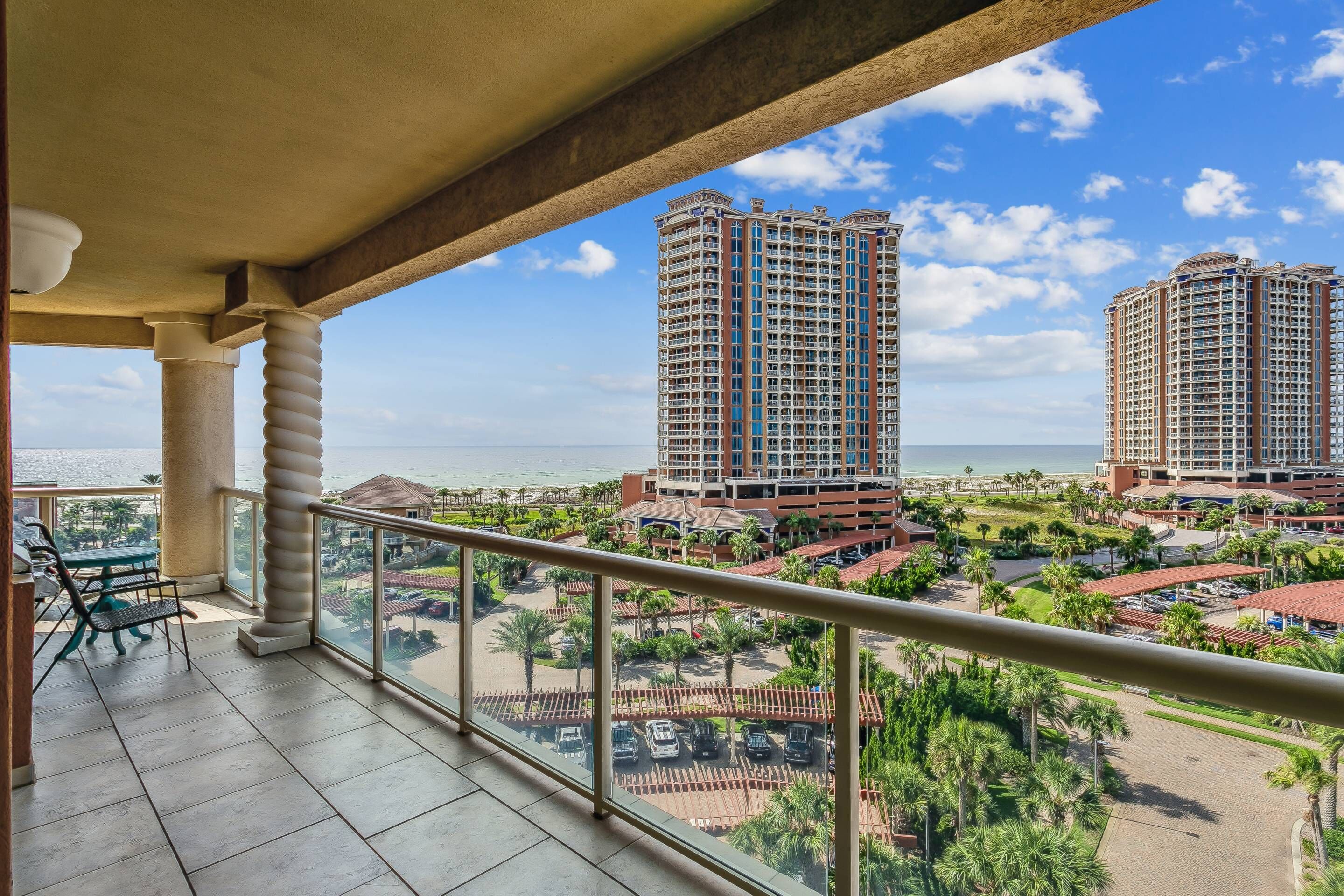 A balcony with a view of high-rise buildings and a beach.