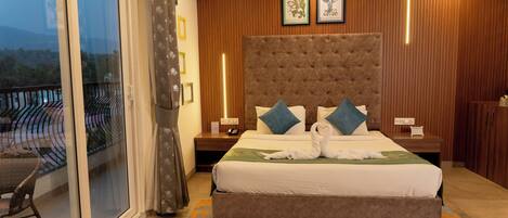 A bedroom with a large bed, a nightstand, a chair, a window with curtains, and wooden paneling on the walls.