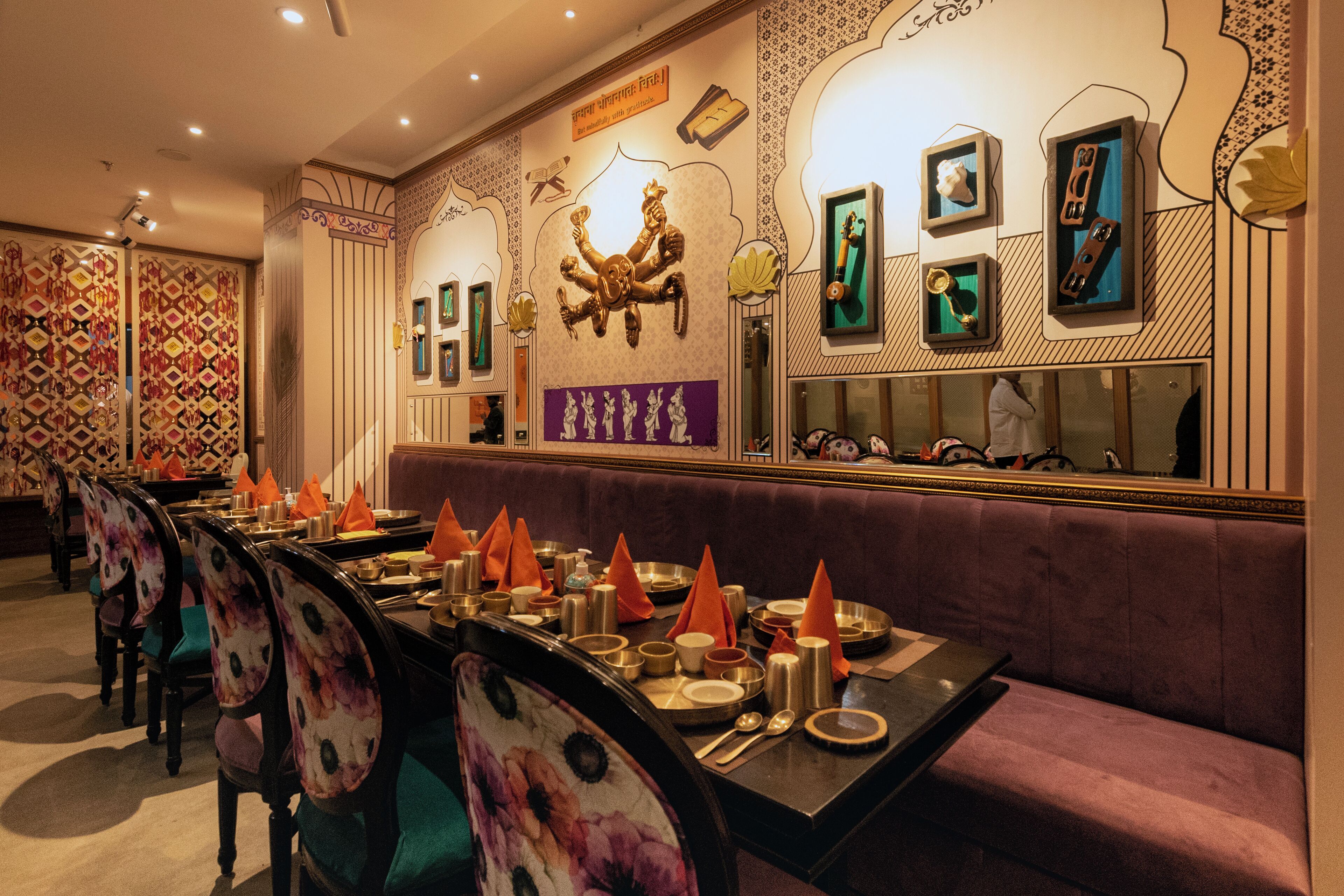 Ein Restaurant mit einem langen Esstisch, violetten Sitzbänken und traditioneller Einrichtung.