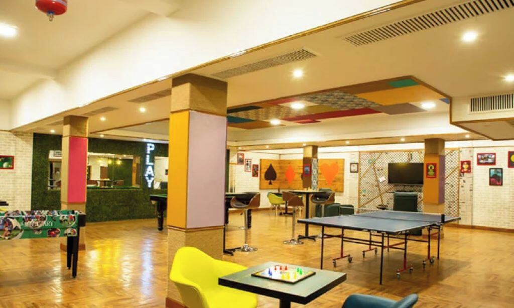 A spacious indoor area with a ping pong table, seating, and a counter with a sign that reads 'PLANT'.