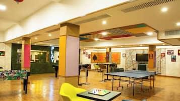 A spacious indoor area with a ping pong table, seating, and a counter with a sign that reads 'PLANT'.