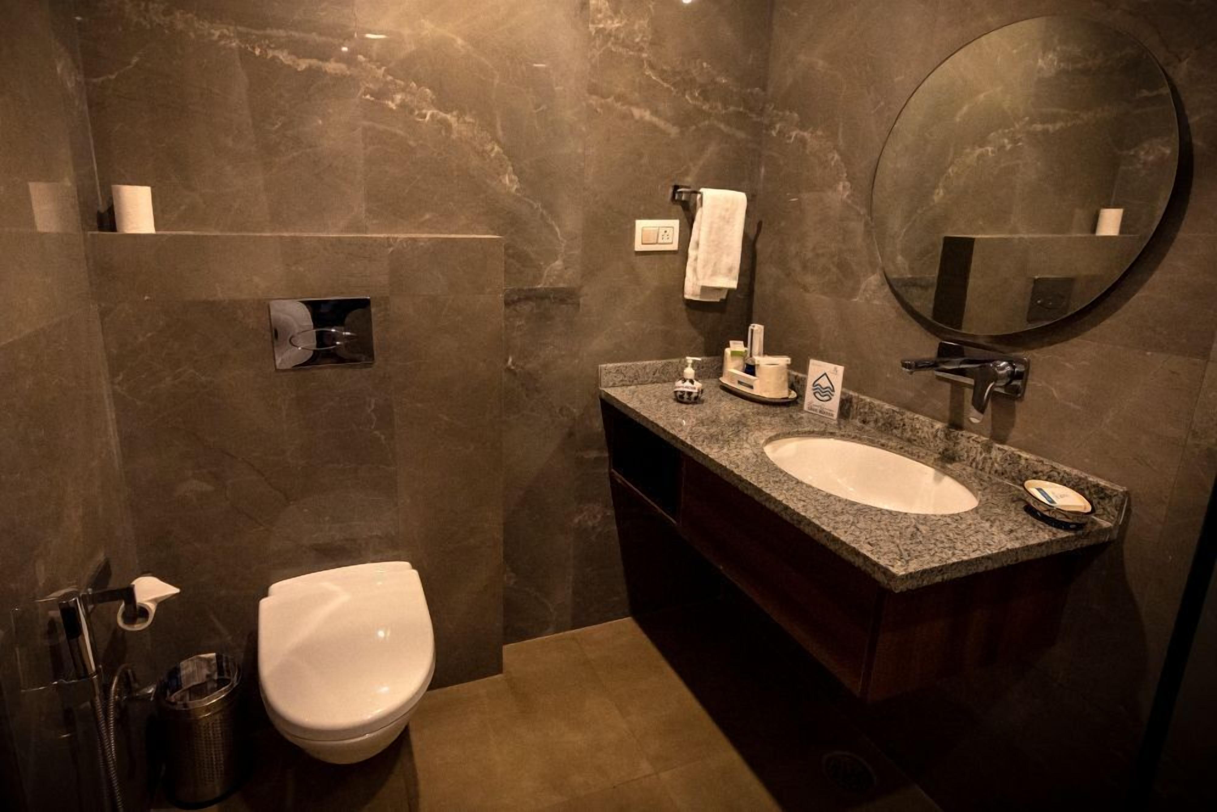 A bathroom with a white toilet, a sink with a mirror, and a towel rack.