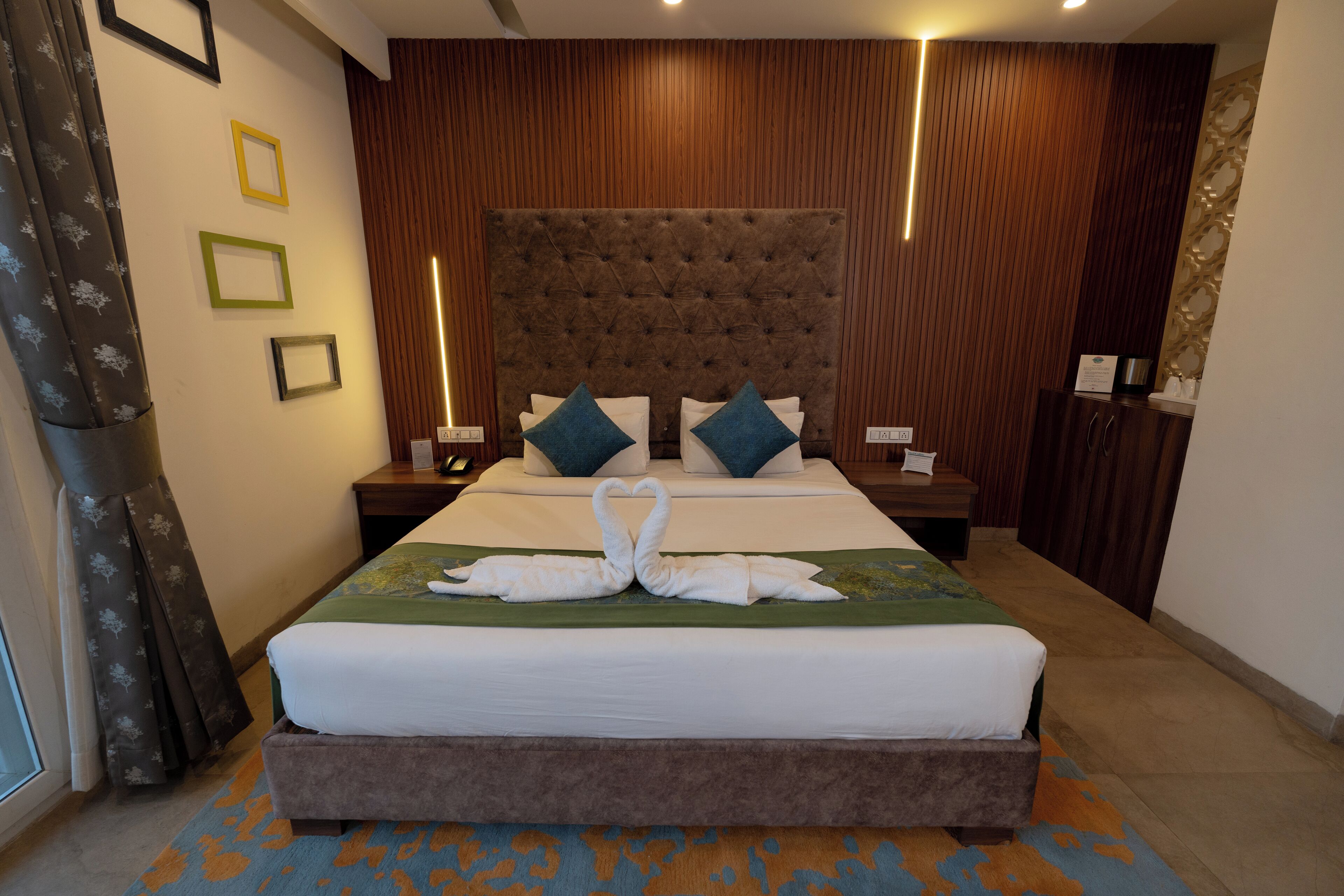 A hotel room with a large bed, two nightstands, a wooden headboard, and a decorative wall panel.