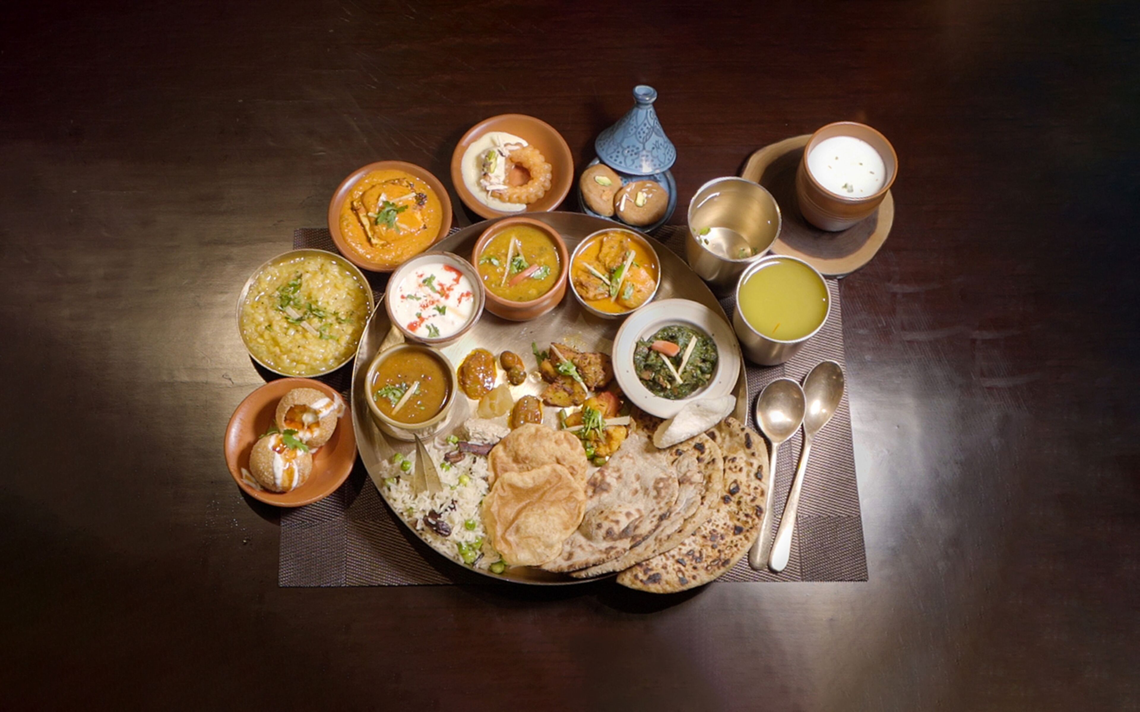 Diversos platos y panes planos dispuestos en una mesa, junto con una tetera y tazas tradicionales.