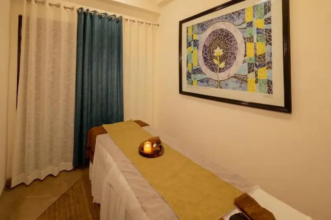 Una habitación con una cama, una mesita con una vela y una obra de arte enmarcada en la pared.
