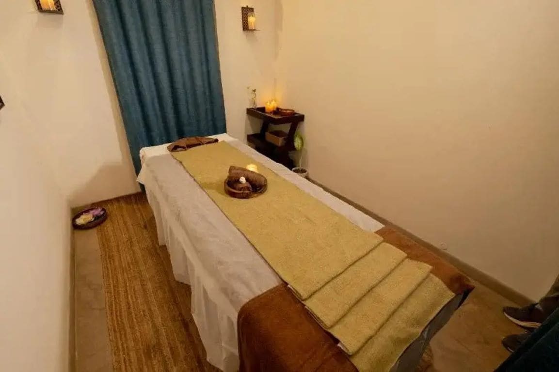 A massage therapy room with a massage table, towels, candles, and a small table with a candle.