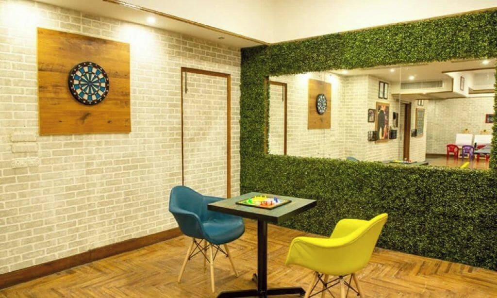 Una habitación con dardos, dos sillas, una mesa y un espejo que refleja el espacio.
