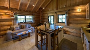 A log cabin interior with a sofa, dining table, and kitchen area.