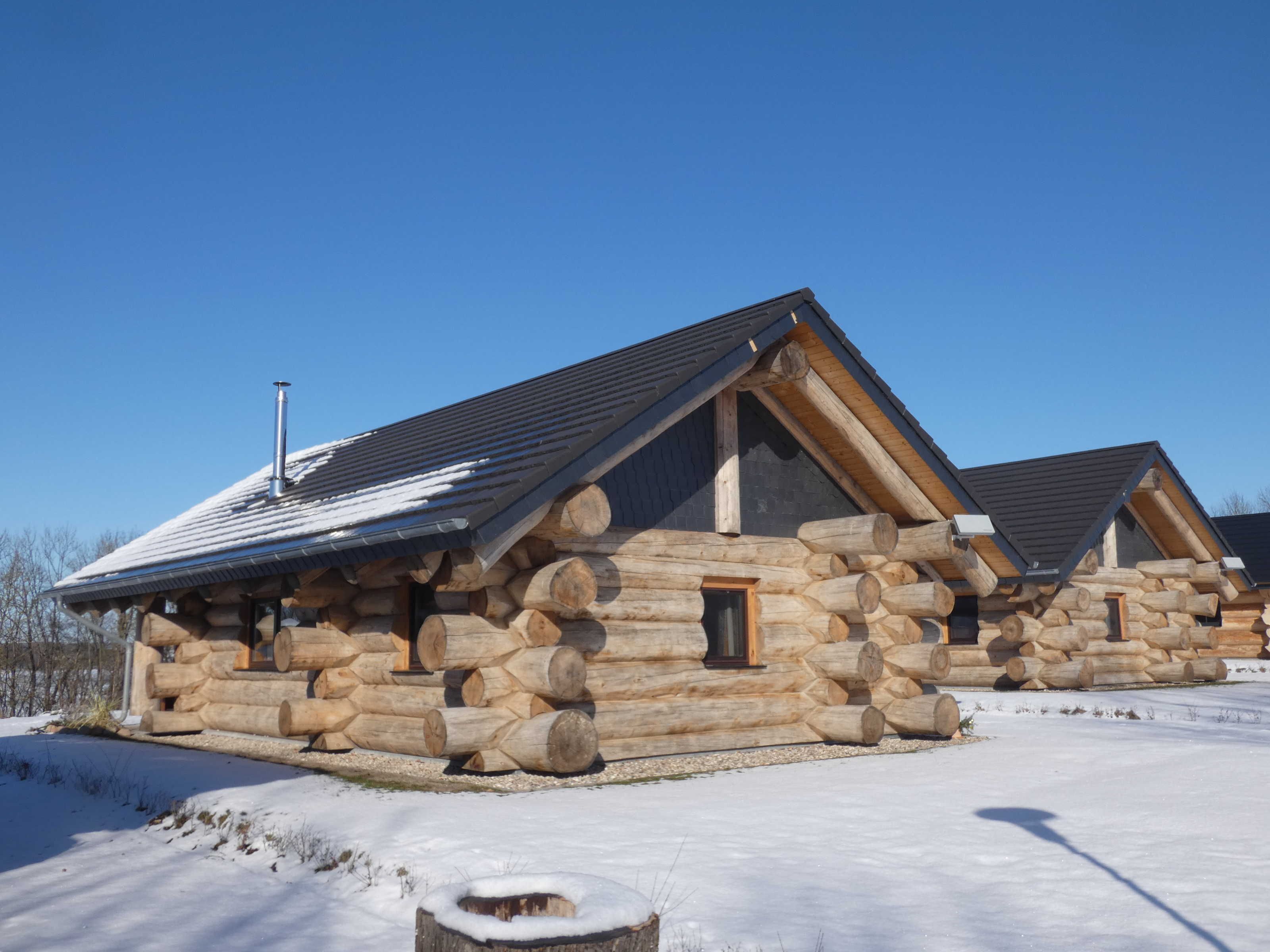 A log cabin with a chimney, a window, and a door.