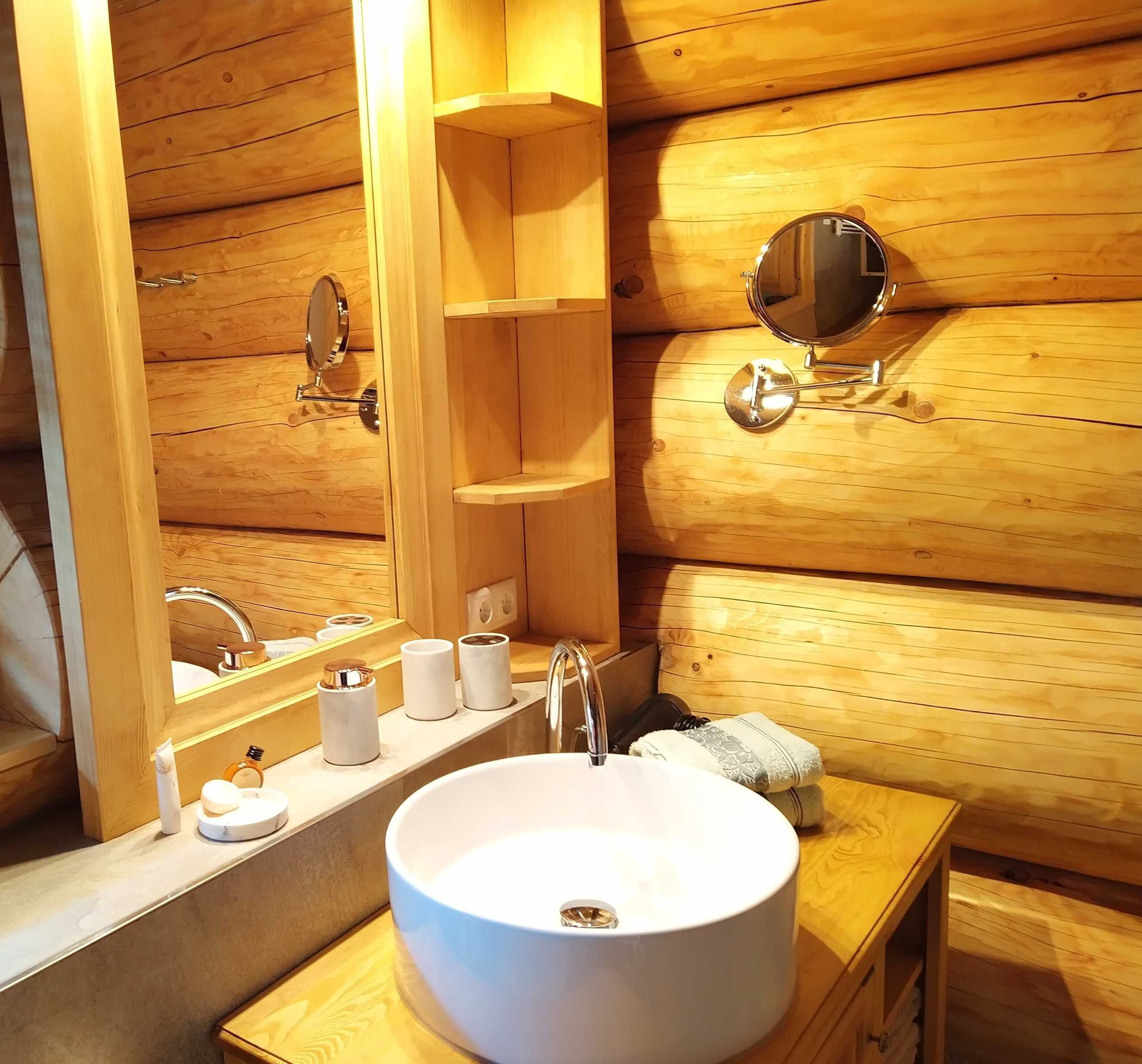 Un baño estilo cabaña de madera con un espejo grande, un lavamanos y un perchero para toallas.