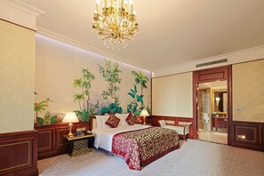 A spacious hotel room with a large bed, a chandelier, a nightstand, a desk, and a bathroom visible through an open door. - Hengda Hotel Jinshazhou (Guangzhou)