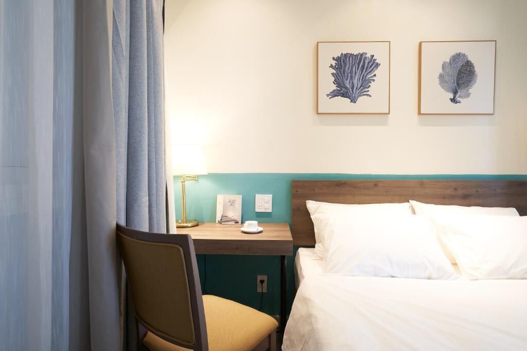 Una habitación de hotel con una cama, un escritorio y dos cuadros enmarcados en la pared.