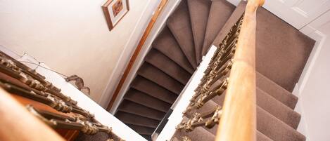 A spiral staircase with a wooden handrail and carpeted steps.