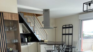 Et moderne køkken med et træskab, et spiseområde med bord og stole, og en trappe til en overetage.