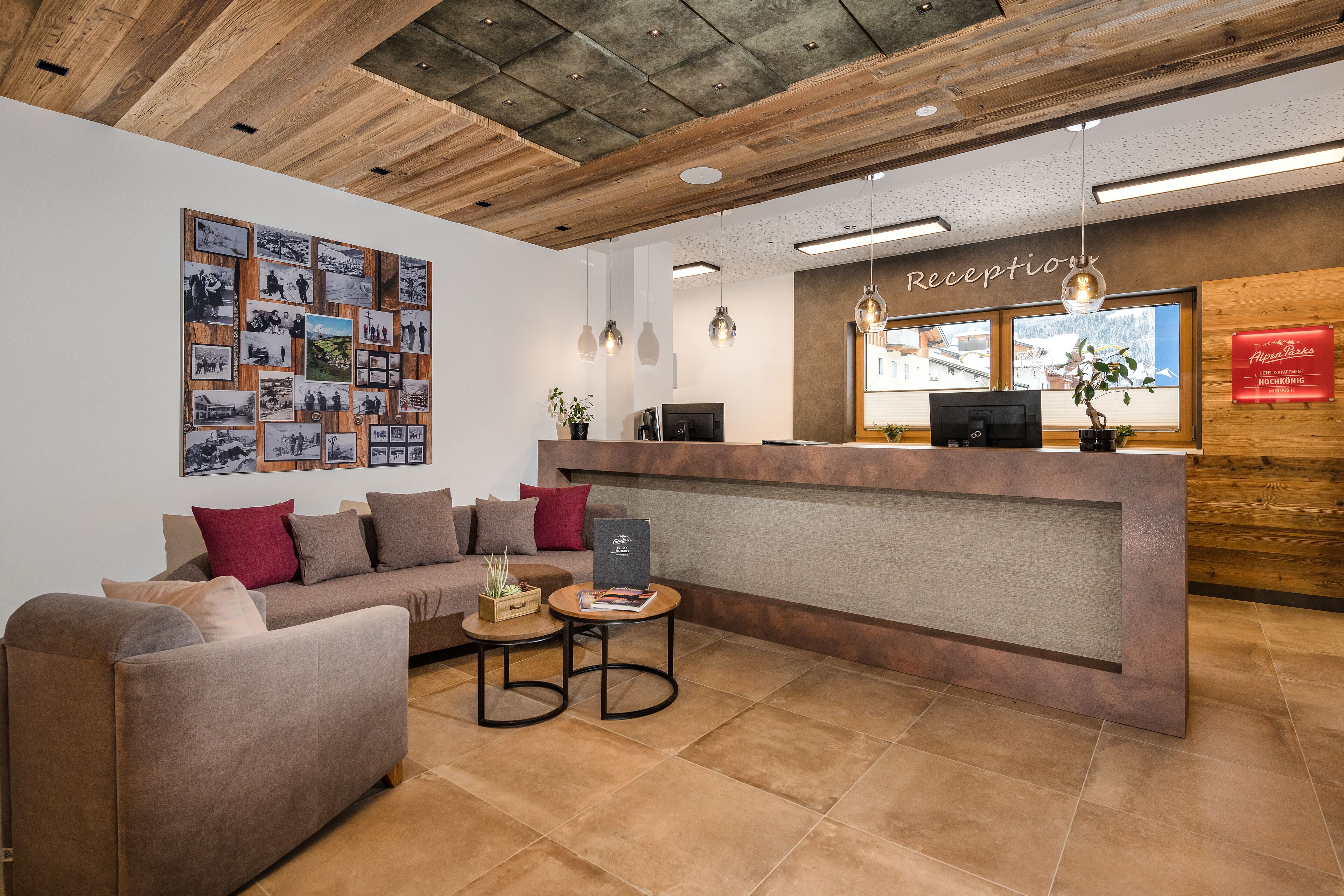 A reception area with a wooden ceiling, a reception desk, a sofa, and a wall with photographs.