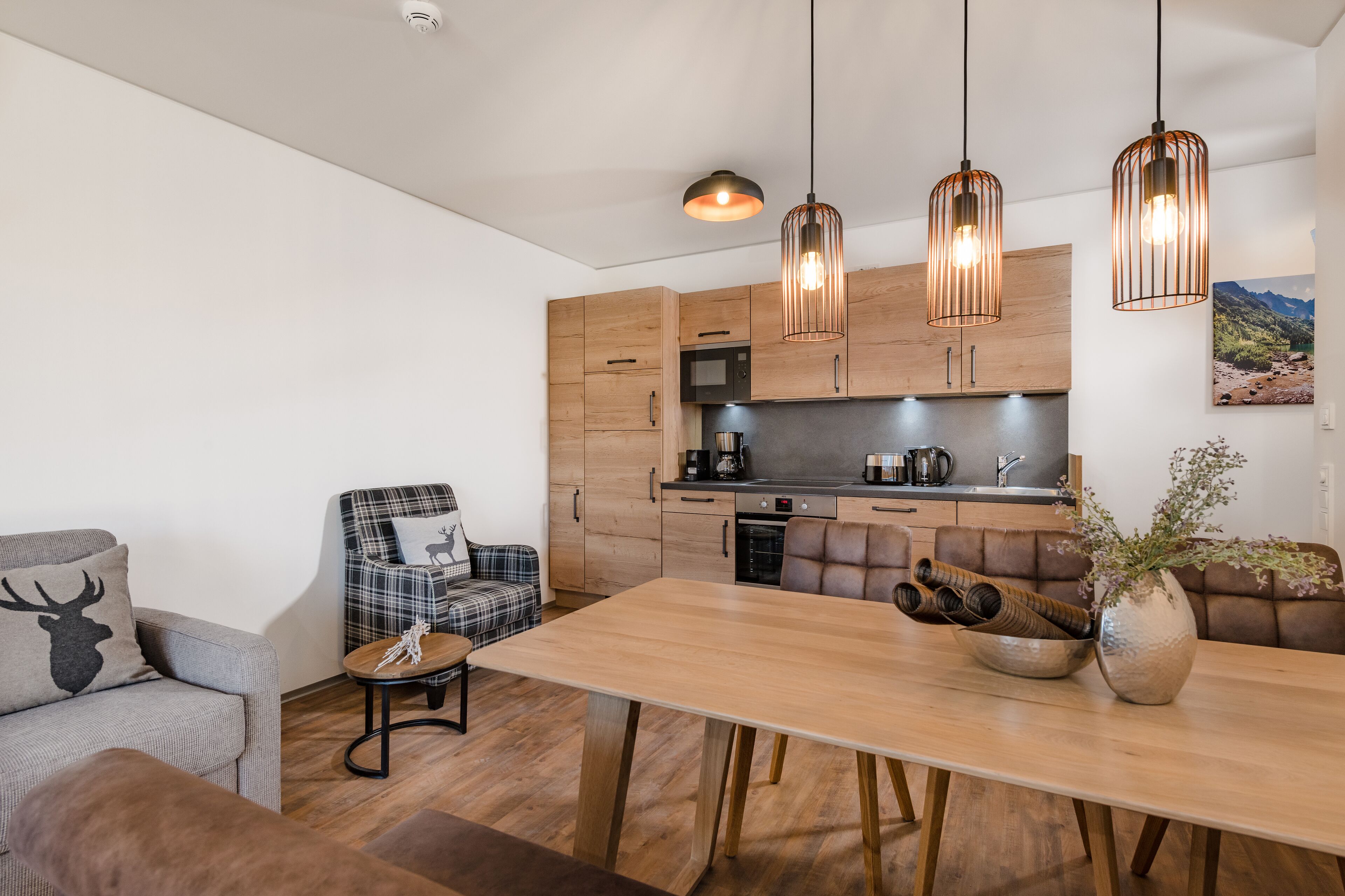 Una cocina moderna con armarios de madera, una mesa de comedor y luces colgantes.