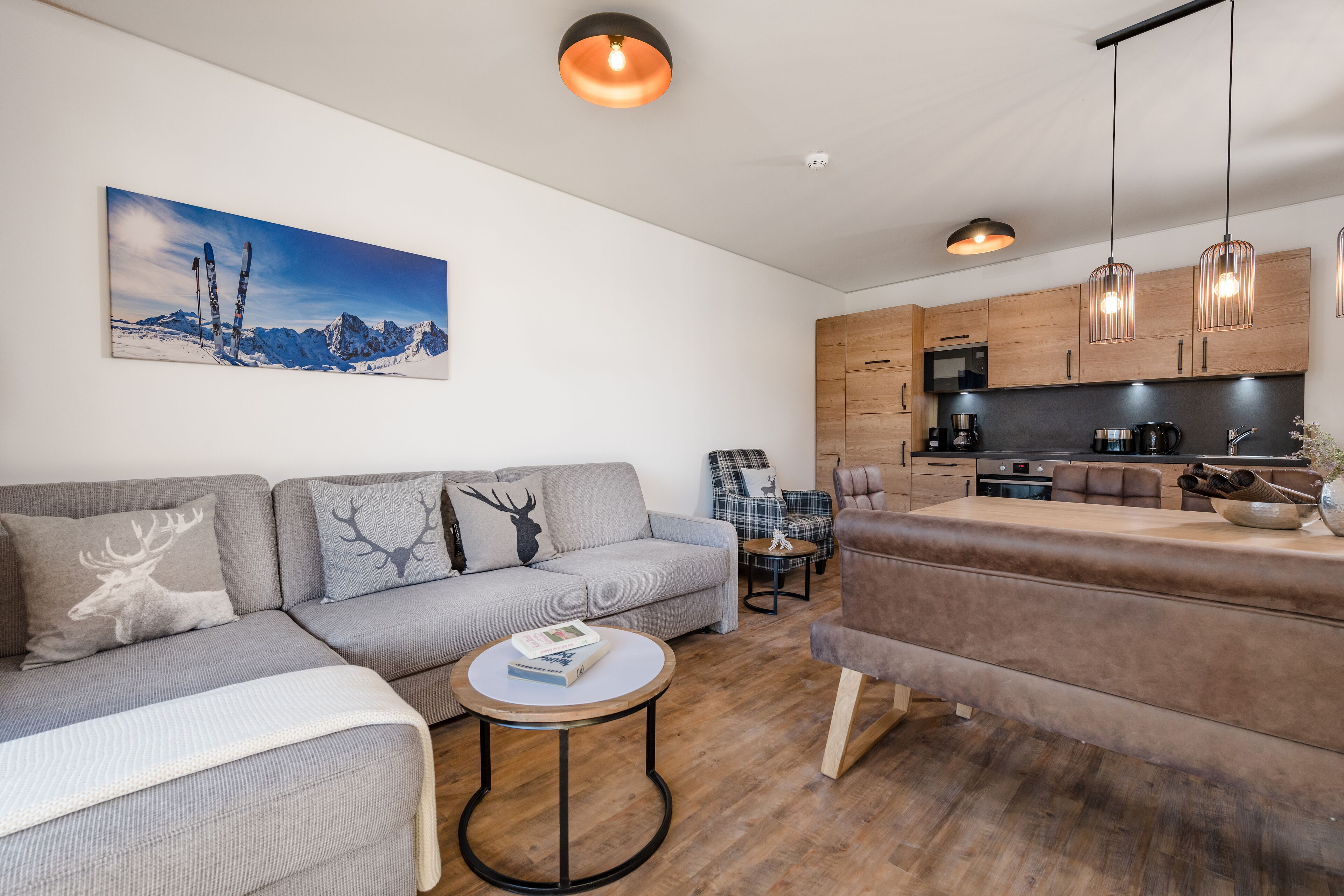 A modern living room with a sofa, a round coffee table, and a painting of a mountain landscape.