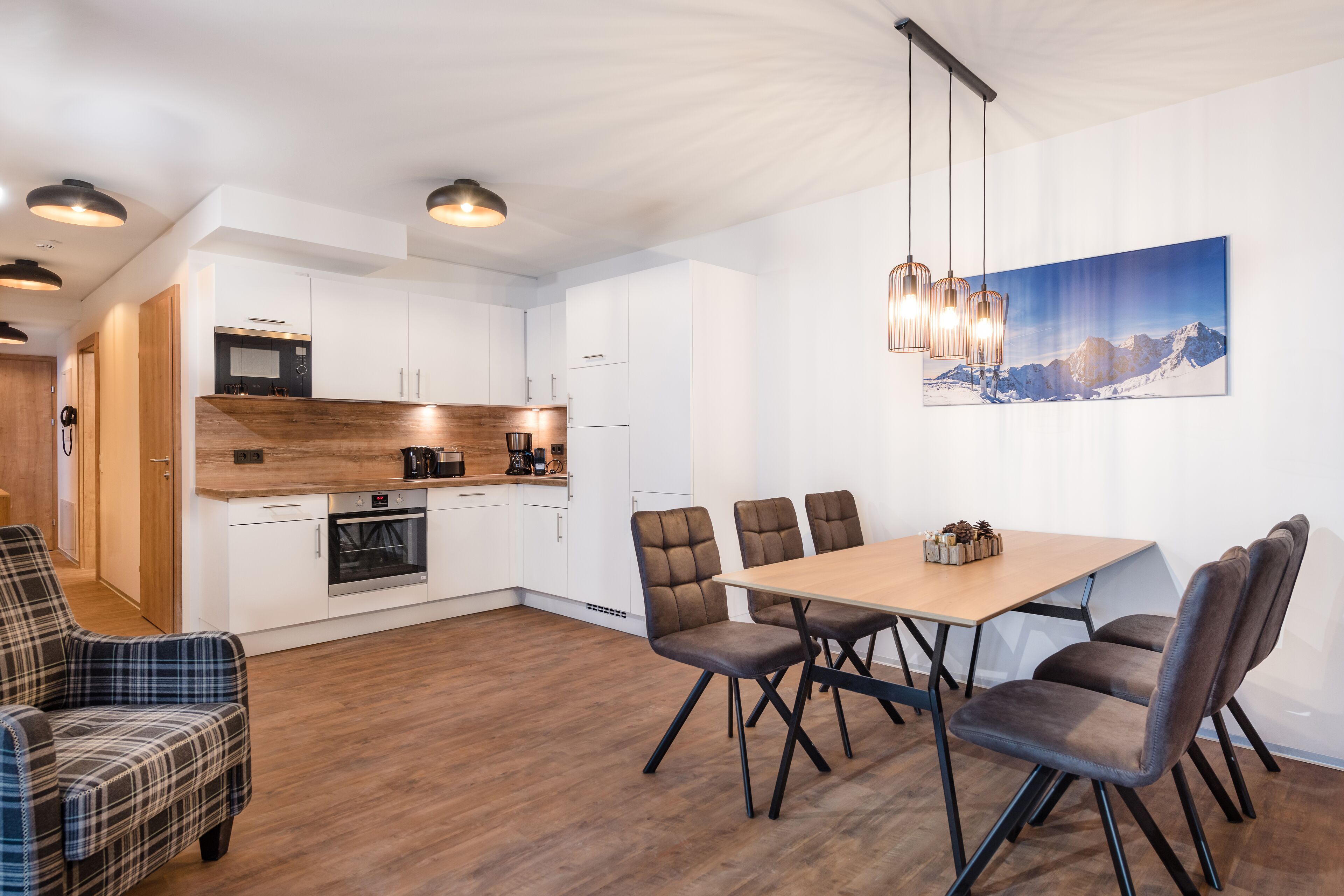 A modern kitchen with white cabinets, a wooden countertop, and a dining area with a table and chairs.