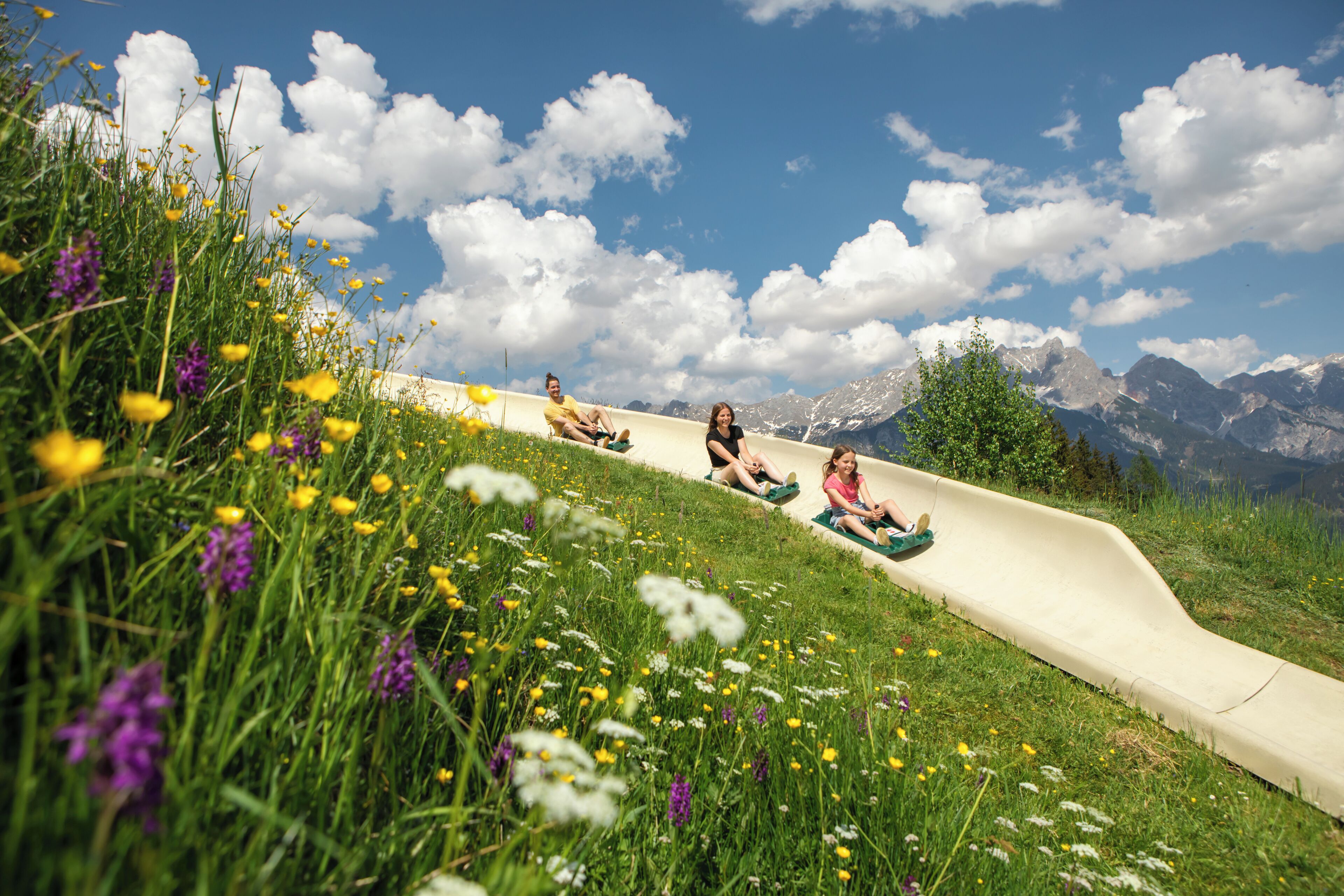 A person sliding down a hill on a green sled.