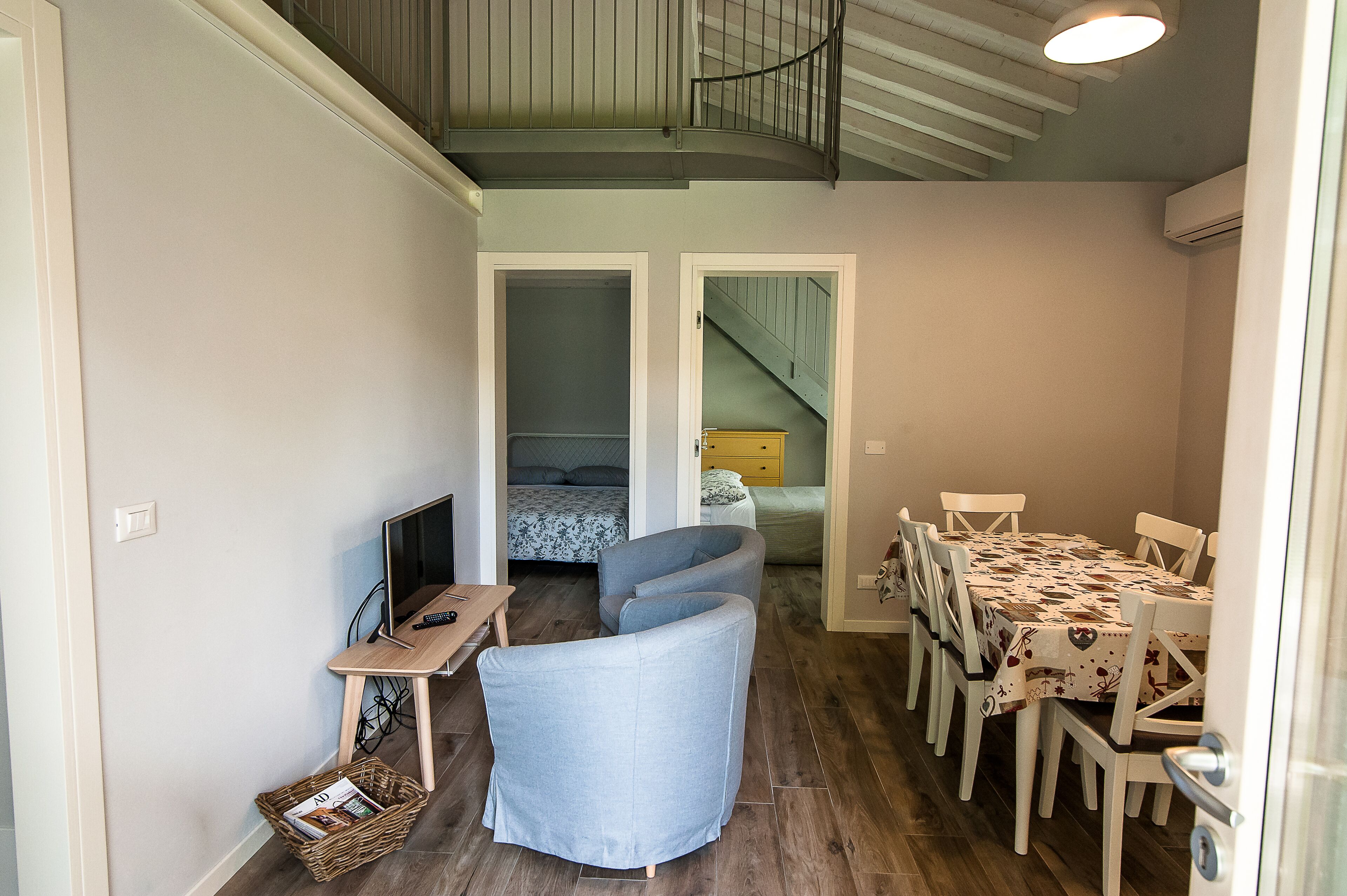 Een compacte woonruimte met een eethoek, een zithoek en een slaapkamer met een trap.