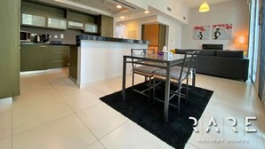 A modern kitchen with a dining area, a sofa, and artwork on the wall. - Stylish 1 Bed apartment in Downtown Dubai (Dubai)