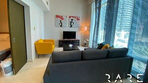 A modern living room with a sofa, a TV, and artwork on the wall. - Stylish 1 Bed apartment in Downtown Dubai (Dubai)